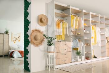 Big wardrobe with different clothes and accessories in studio apartment�