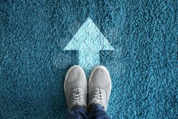 Man standing on carpet with arrow pointing in one direction. Concept of choice�