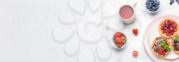 Sweet tartlets, berries and tea on light background  with space for text�