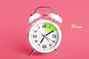 Alarm clock with timer for 10 minutes on color background. Time management concept�