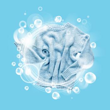 Clean sweater with soap bubbles on color background�