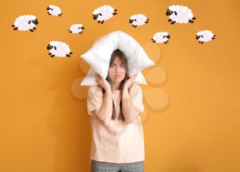 Tired woman with pillow on color background. Concept of sleep deprivation�
