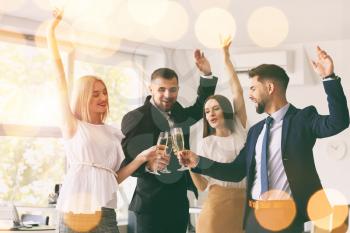 Young people clinking glasses of tasty champagne at party in office�