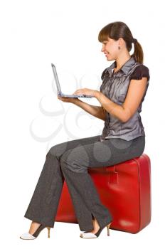 Royalty Free Photo of a Girl Sitting on a Suitcase Holding a Laptop