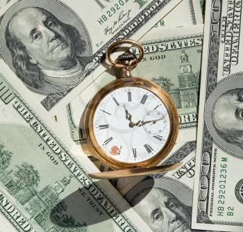 Time and Money concept image.
us currency and a pocket watch portray time and money.Business concept.
