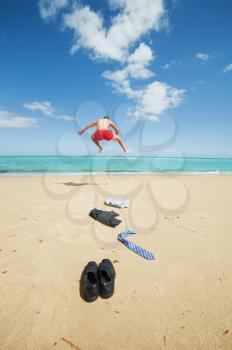 young businessman jumping on the beach after a big deal