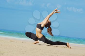 Young woman making exercise on the beach.
