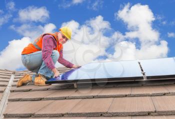 experienced worker checking solar panels on house roof