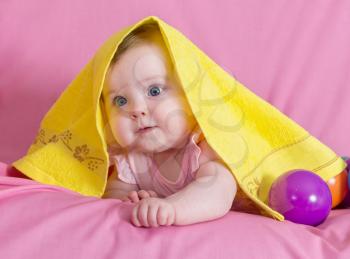 Adorable happy baby girl with yellow  towel on pink background 
