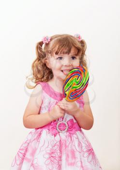 Portrait of cute little girl with big colorful lollipop  on a light background