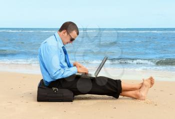 young businessman working with laptop on the beach 