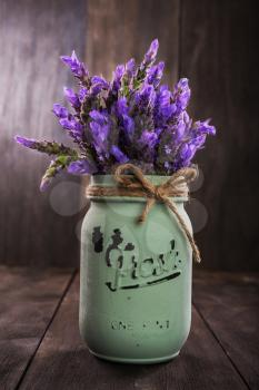 bundle of lavender flowers in retro vase isolated on an old wooden background