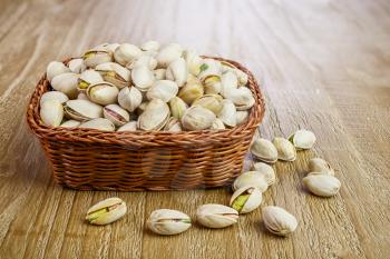 Pistachios nuts  in wicker basket on vintage wooden table