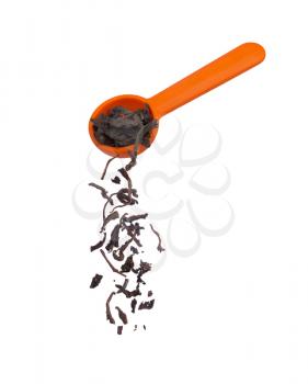 dry black tea falling from orange spoon  isolated on white