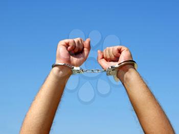 Royalty Free Photo of Handcuffed Hands Against a Blue Sky