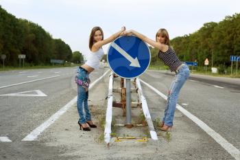 Royalty Free Photo of a Two Women on the Road by a Sign