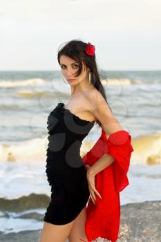 Portrait of beautiful young brunette in black dress on the beach