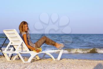 Cheerful teenage girl sitting on a lounge chair