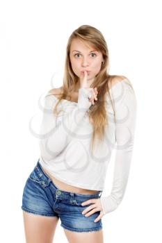 Pretty young woman in white blouse and blue jeans shorts shows gesture to be quiet. Isolated
