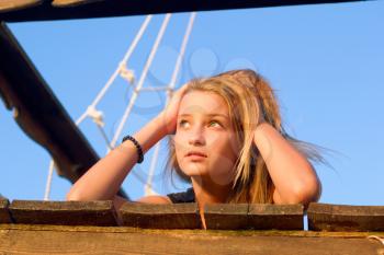 Dreamy girl lying on the deck of an old wooden ship