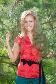 Smiling blond woman posing near the pine