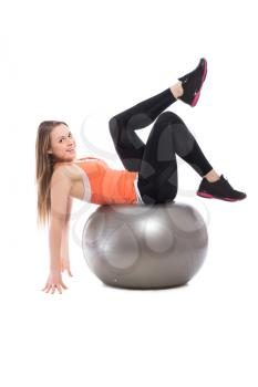Young smiling woman doing exercises on a grey fit. Isolated
