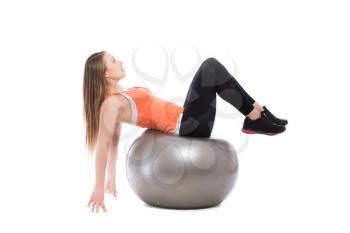 Young blonde posing on grey fit ball. Isolated