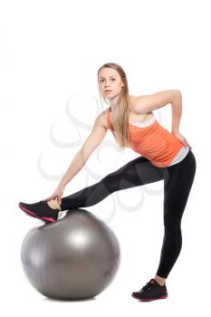 Sporty slim blonde posing with a fit ball. Isolated