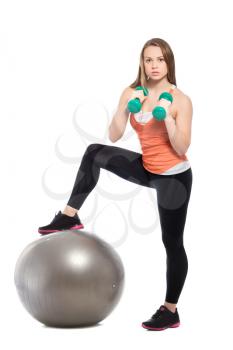 Sporty slim blonde posing with a fit ball and dumbbells. Isolated