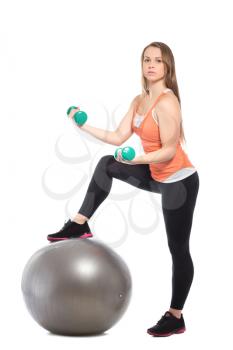 Slim blond woman posing with a fit and dumbbells. Isolated