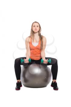Pretty blonde sitting on a fit with dumbbells. Isolated
