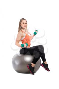 Young sporty woman training with dumbbells on a fit. Isolated