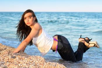 Sexy young woman in jeans posing on the beach