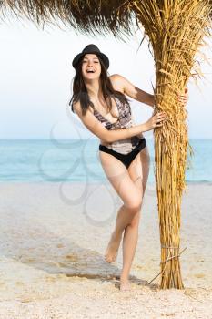 Young smiling woman posing in grey hat on the beach