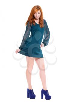Attractive redhead woman playing with her dress. Isolated on white