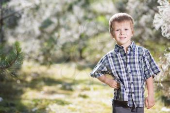 Nice little boy in checked shirt posing outdoors