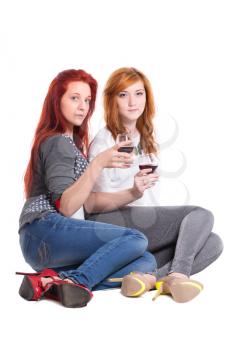 Two redhead women sitting and holding glasses of wine. Isolated on white