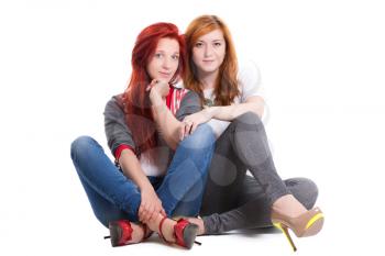 Two pretty redhead women sitting. Isolated on white