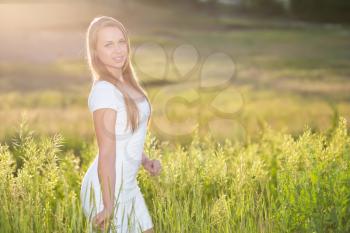 Cute young blonde wearing white dress posing outdoors