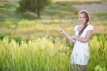 Seductive young blonde wearing white dress posing on the meadow