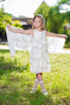 Beautiful little girl wearing white dress posing outdoors