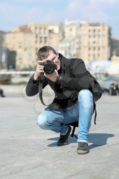 Young man with professional camera taking photograph outdoors