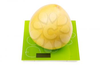 Pomelo fruit on square kitchen scales. Isolated
