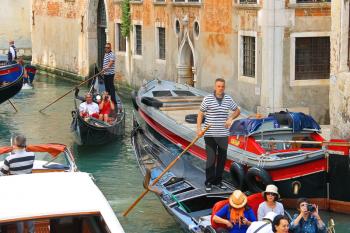 VENICE, ITALY - MAY 06, 2014: Several gondolas with tourists in a narrow channel. Venice, Italy