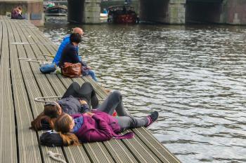 Amsterdam, the Netherlands - October 03, 2015: People resting at berth near the water