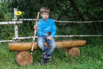 Boy with wooden sword sitting on log bench