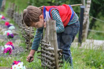 Boy with wooden sword near original flowerbed with decorative fence