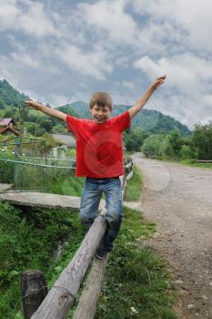 Smiling boy on fence log in Carpathians, Ukraine