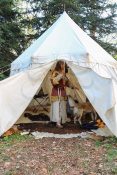 Spilamberto, Italy- October 02, 2016: Woman in ancient style dress with dog in a tent