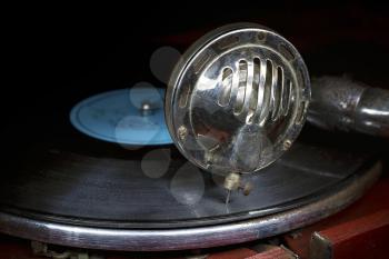 Head with an old gramophone needle on the vinyl disc closeup